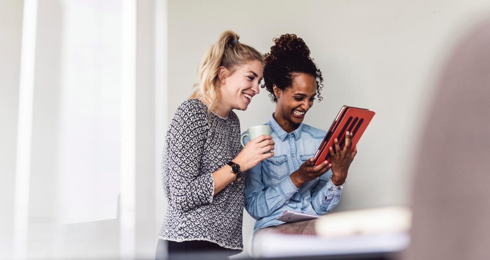 Two girls laughing looking at ipad