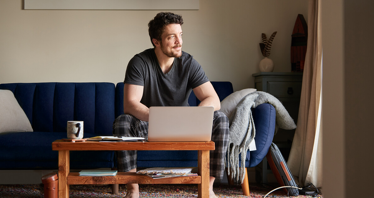 Man sitting on couch with laptop on desk